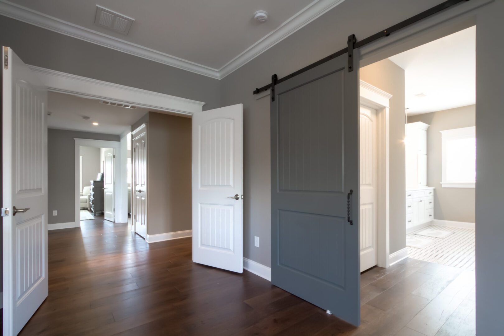 Gray barn door and hardwood floor hallway.