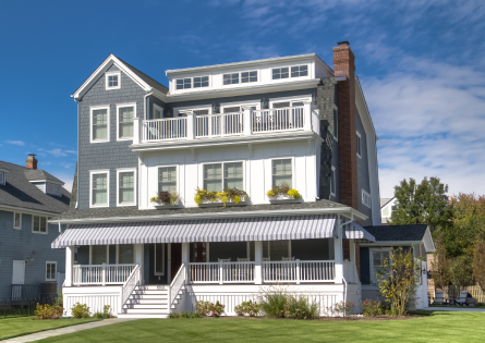 Large blue beach house with porch.