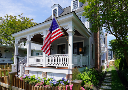 American flag on white porch of house.