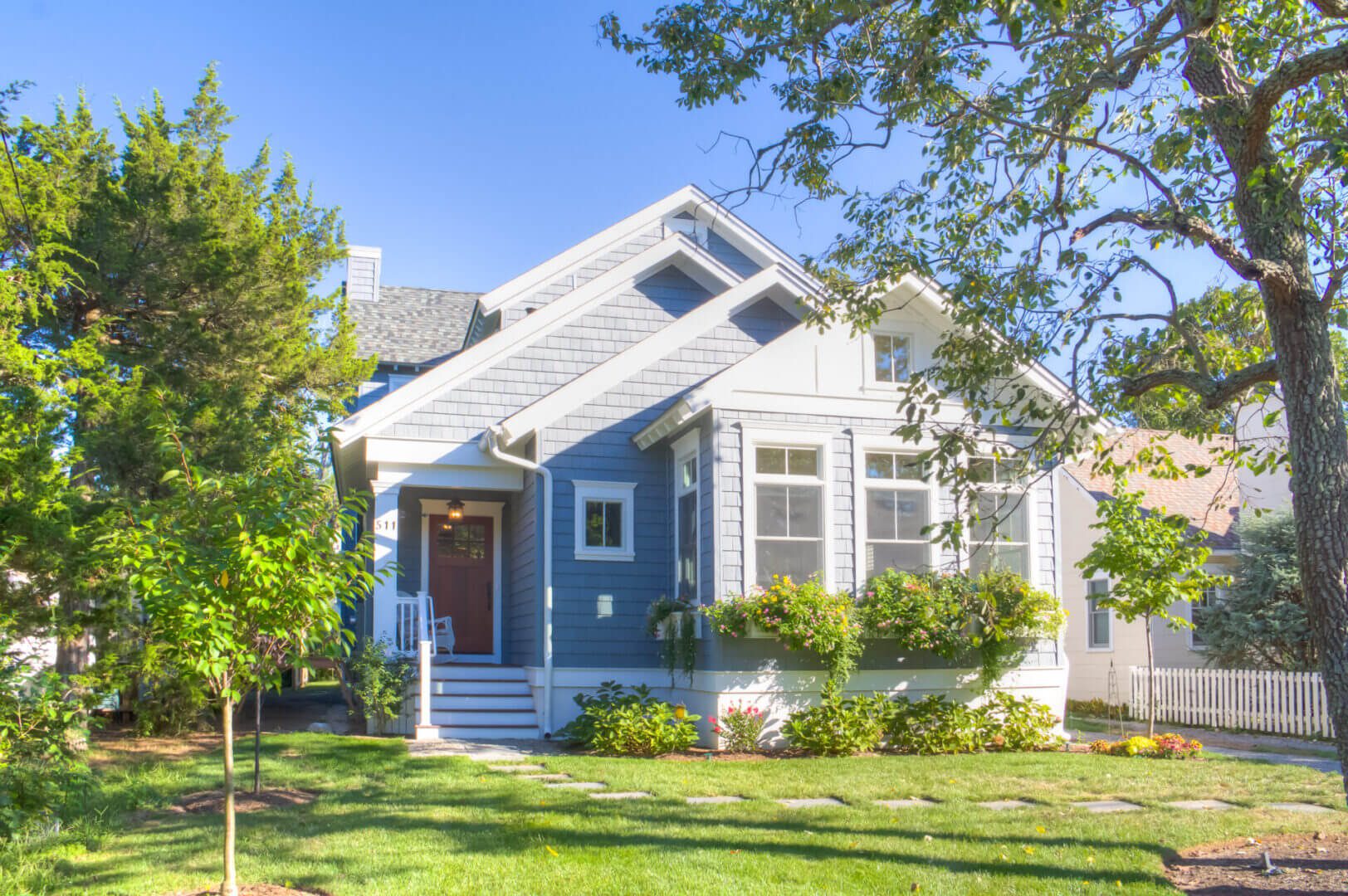 Gray house with flowers and green lawn.