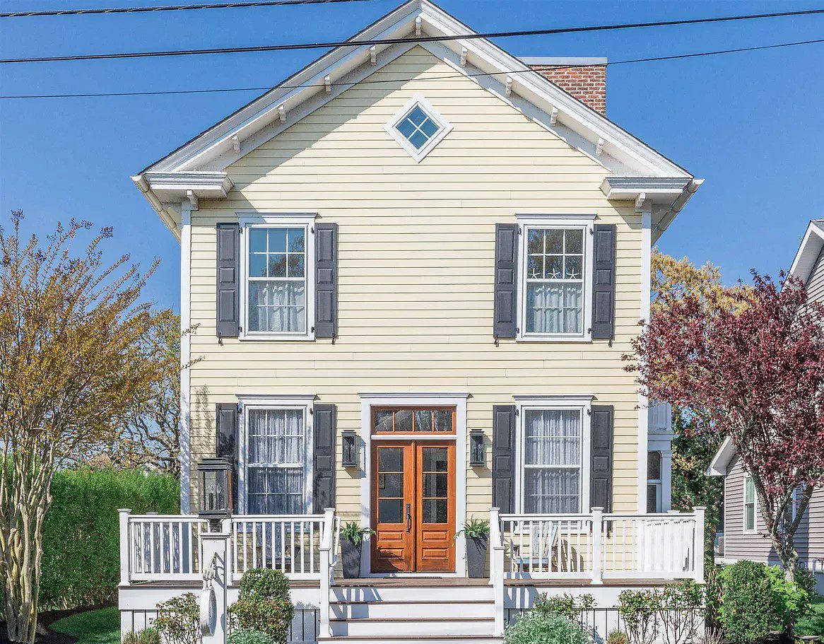 Yellow house with porch and shutters.