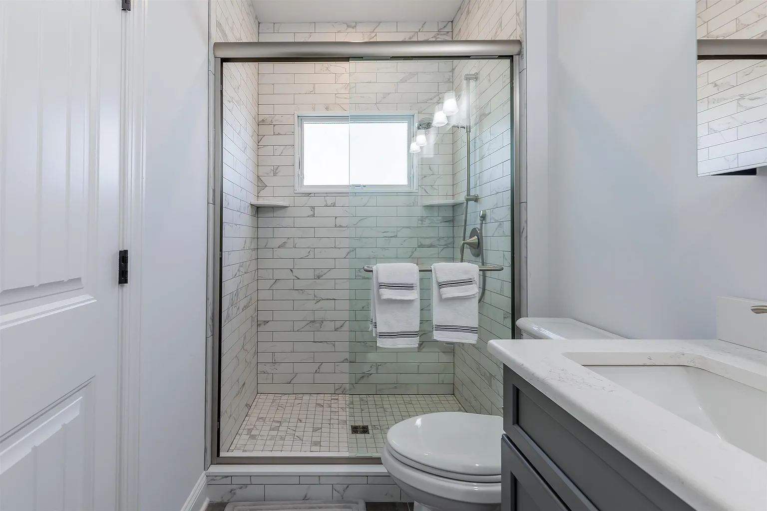Small white tiled shower with toilet.